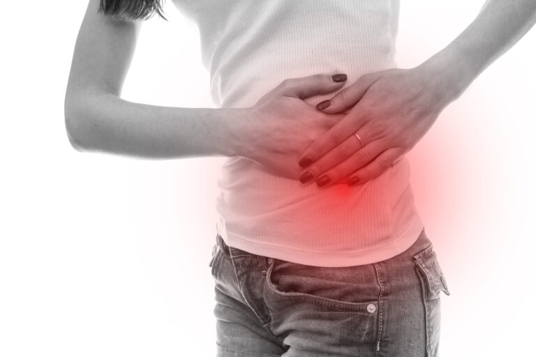 A person holding their lower back with a red glow highlighting the painful area, wearing a white t-shirt and gray jeans, against a white background